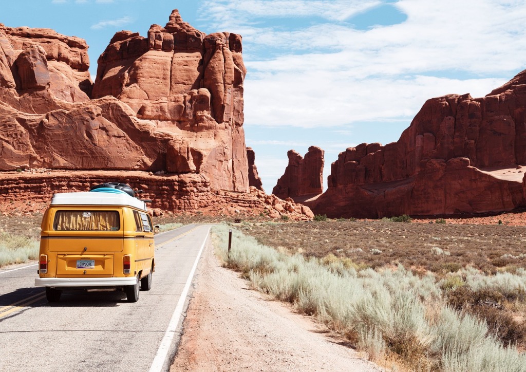 The back of a yellow van is pictured travelling down a dessert roadway.