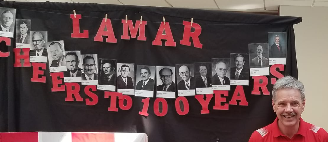 Photographs of the last 100 years of Lamar University presidents is strung between red letters reading 
Cheers to 100 Years" below them and "LAMAR" clothes pinned above. President Jaime Taylor agreed to be photographed with his photo in the display. 